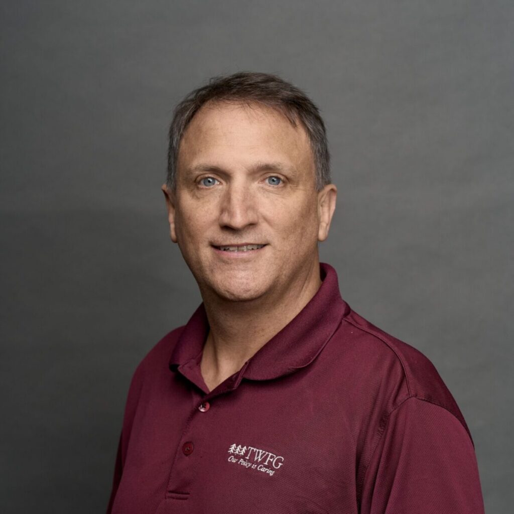 Professional headshot of a man wearing a maroon TWFG polo shirt against a gray background